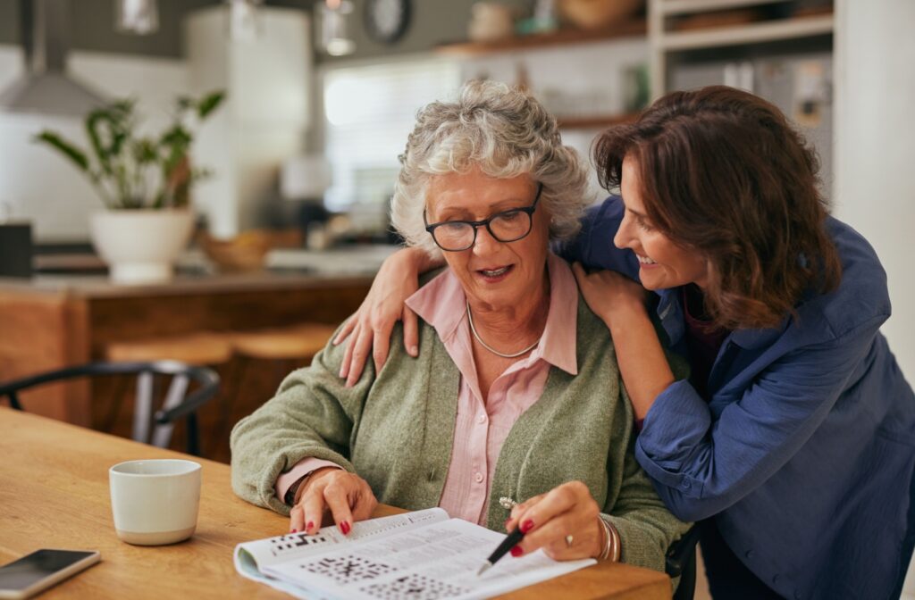 An adult celebrates their older parent with dementia after they have successfully finished a crossword puzzle