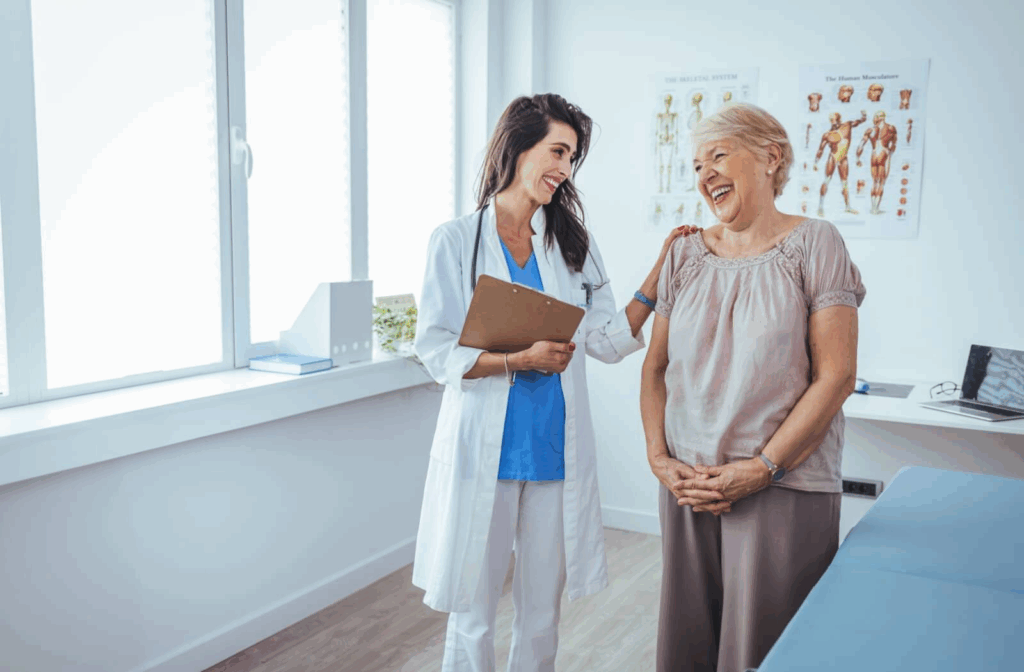 A senior laughs with their doctor during a visit to evaluate their health for assisted living eligibility requirements