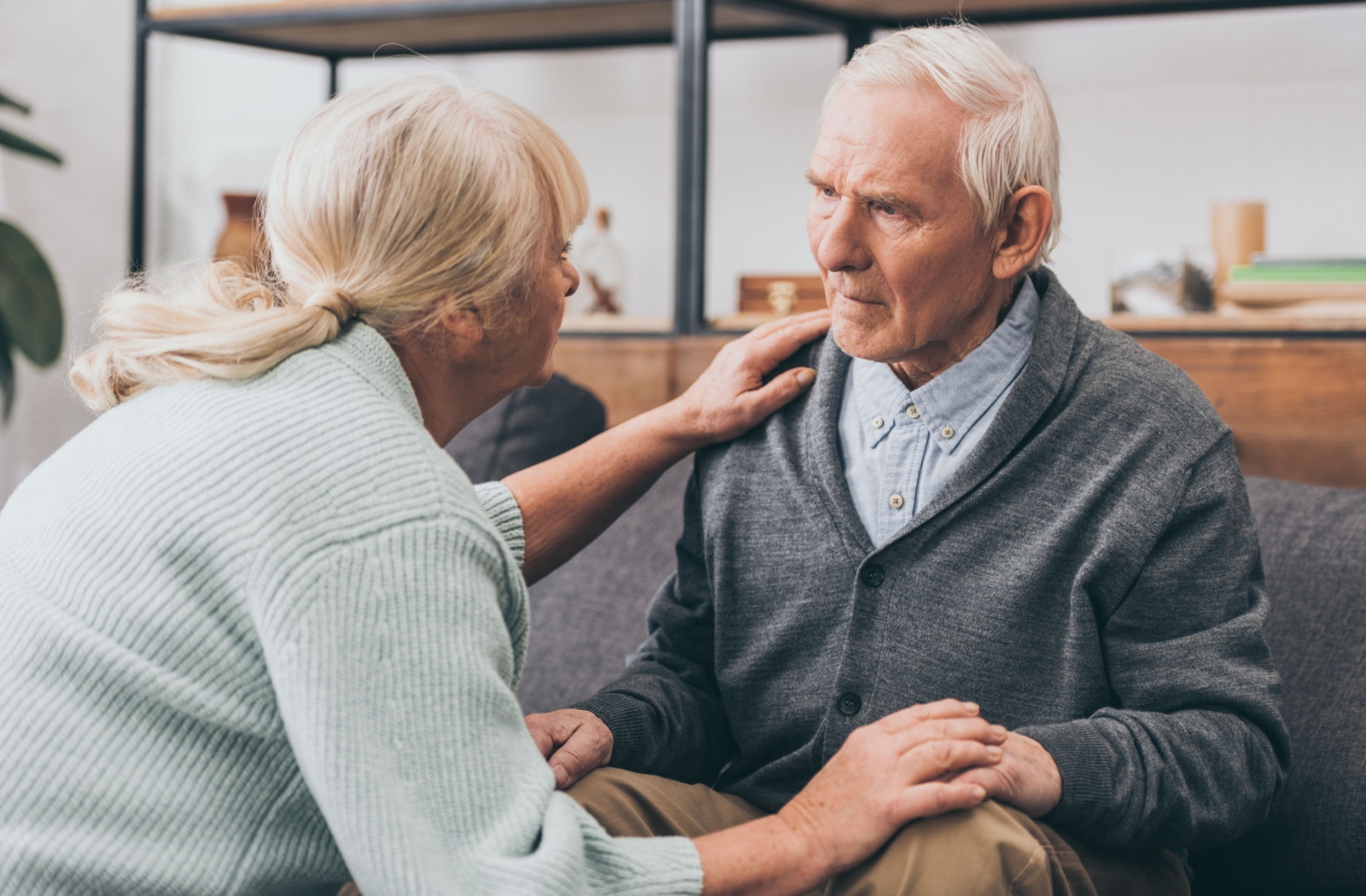 A senior spouse comforts their loved one with dementia in a memory care community.