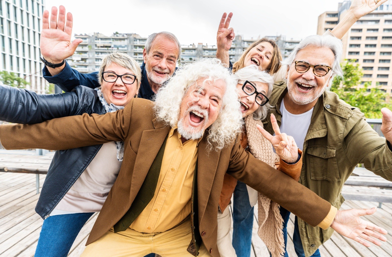 A group of seniors smile and pose for the camera in front of an urban backdrop.
