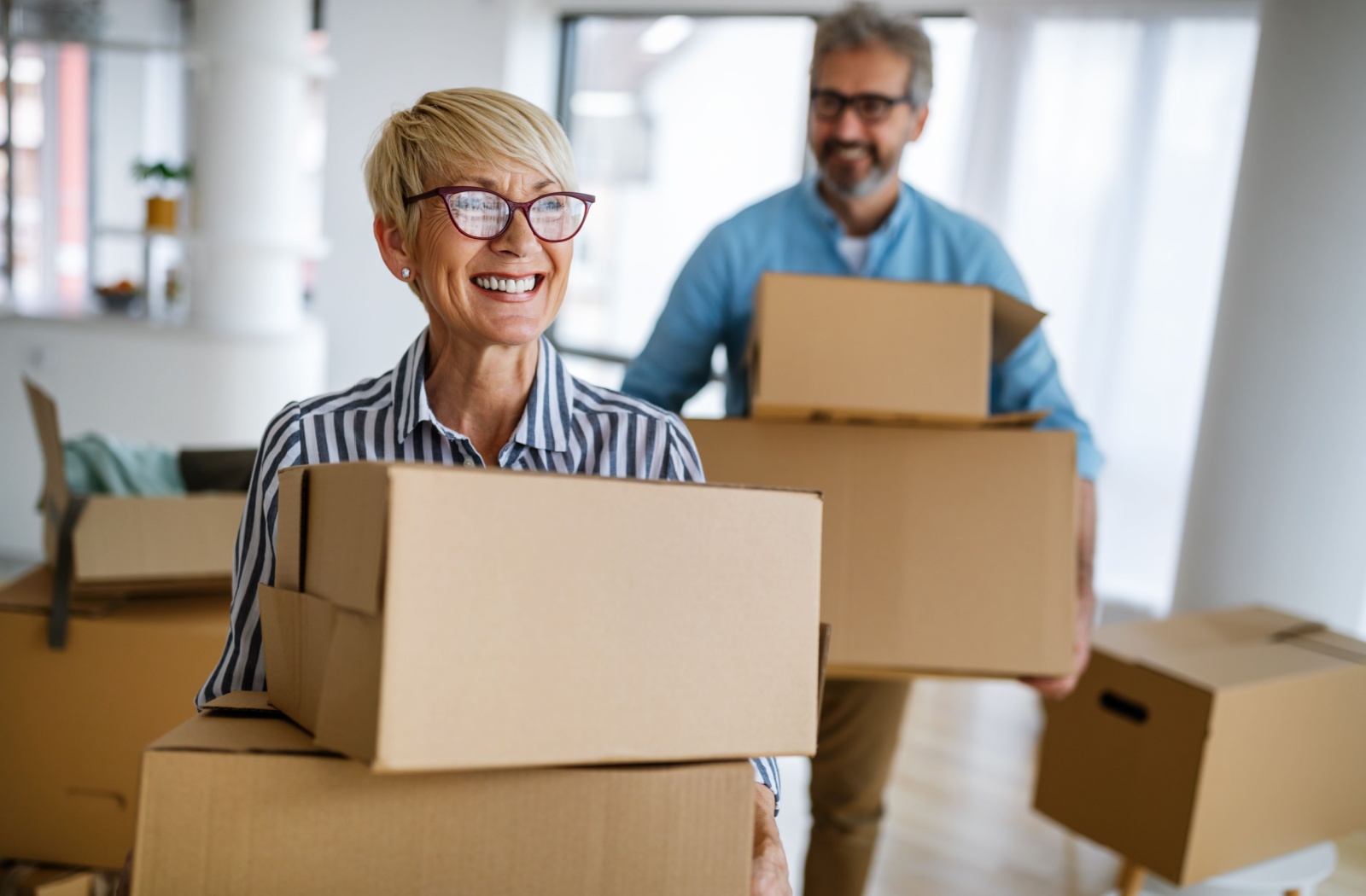 Two older adults pack moving boxes as they downsize their home to move into independent living
